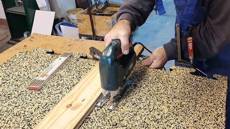 In this photo, a WARCO flooring tile in puzzle form is being cut with a jigsaw. The flexible material can be worked easily with standard tools, allowing for custom fitting. This way, the floor covering can be precisely adapted to edges, corners, and recesses. The sturdy and elastic surface remains intact, ensuring a long-lasting, low-maintenance solution.