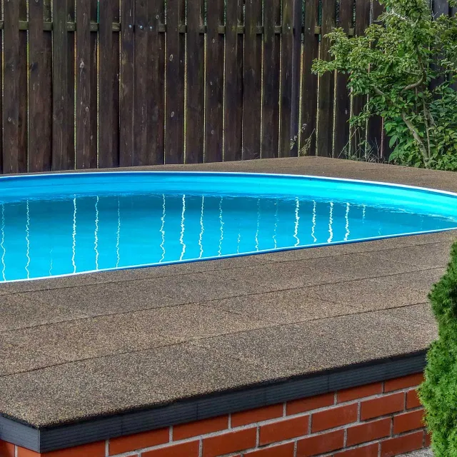 A swimming pool was installed in the garden not at ground level, but raised by around 50 cm. A terrace was created around the pool. The pool surround made of WARCO swimming pool tiles in the terracotta color design is flush with the top edge of the pool.